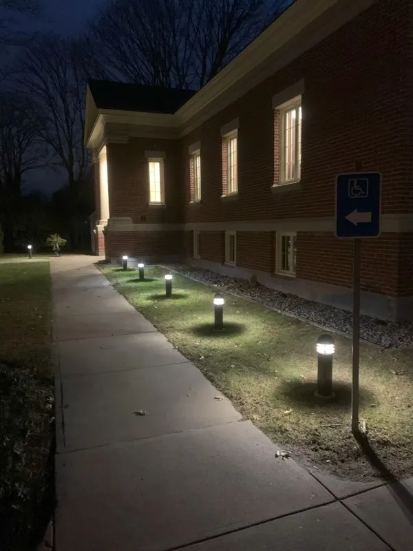 Same commercial brick building at night with bollard and window lighting illuminated