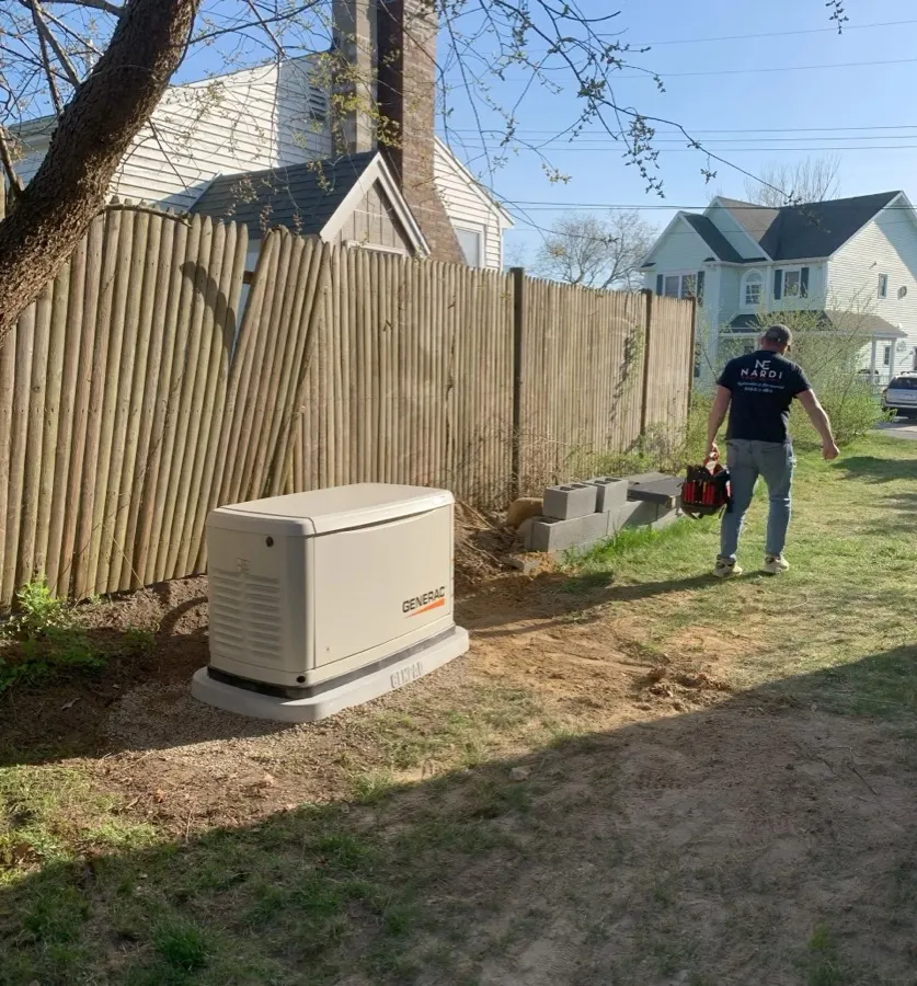 Nardi Electric technician carrying tools past a newly installed Generac home generator